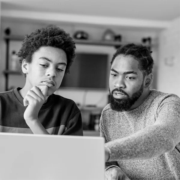 teenager and parent or guardian looking at a laptop screen together in a home environment