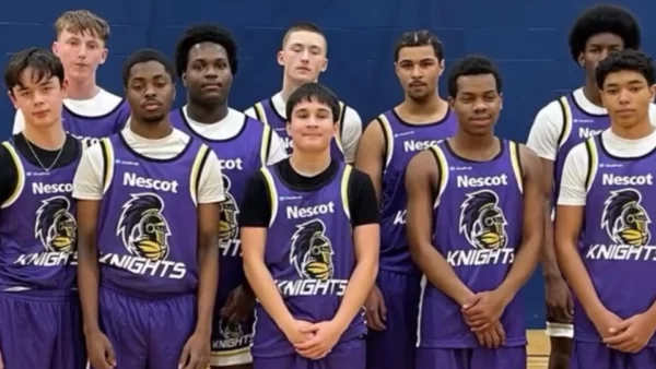A group of basketball players standing together in a sports hall, wearing matching purple Nescot Knights jerseys with a stylised knight helmet logo on the front.