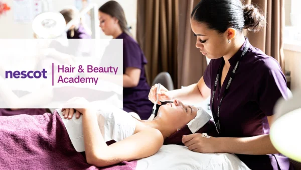 A person lying on a treatment bed while a practitioner applies a beauty treatment in a training salon. The Nescot Hair & Beauty Academy logo appears on the left side of the image.