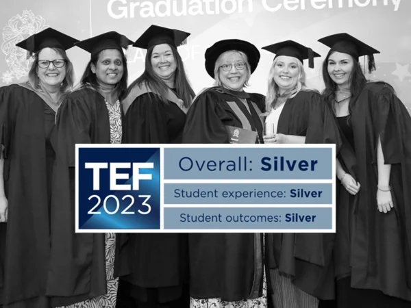 Group of graduates wearing academic gowns at a graduation ceremony, with a logo and graphic displaying “TEF 2023 – Overall: Silver, Student experience: Silver, Student outcomes: Silver”.