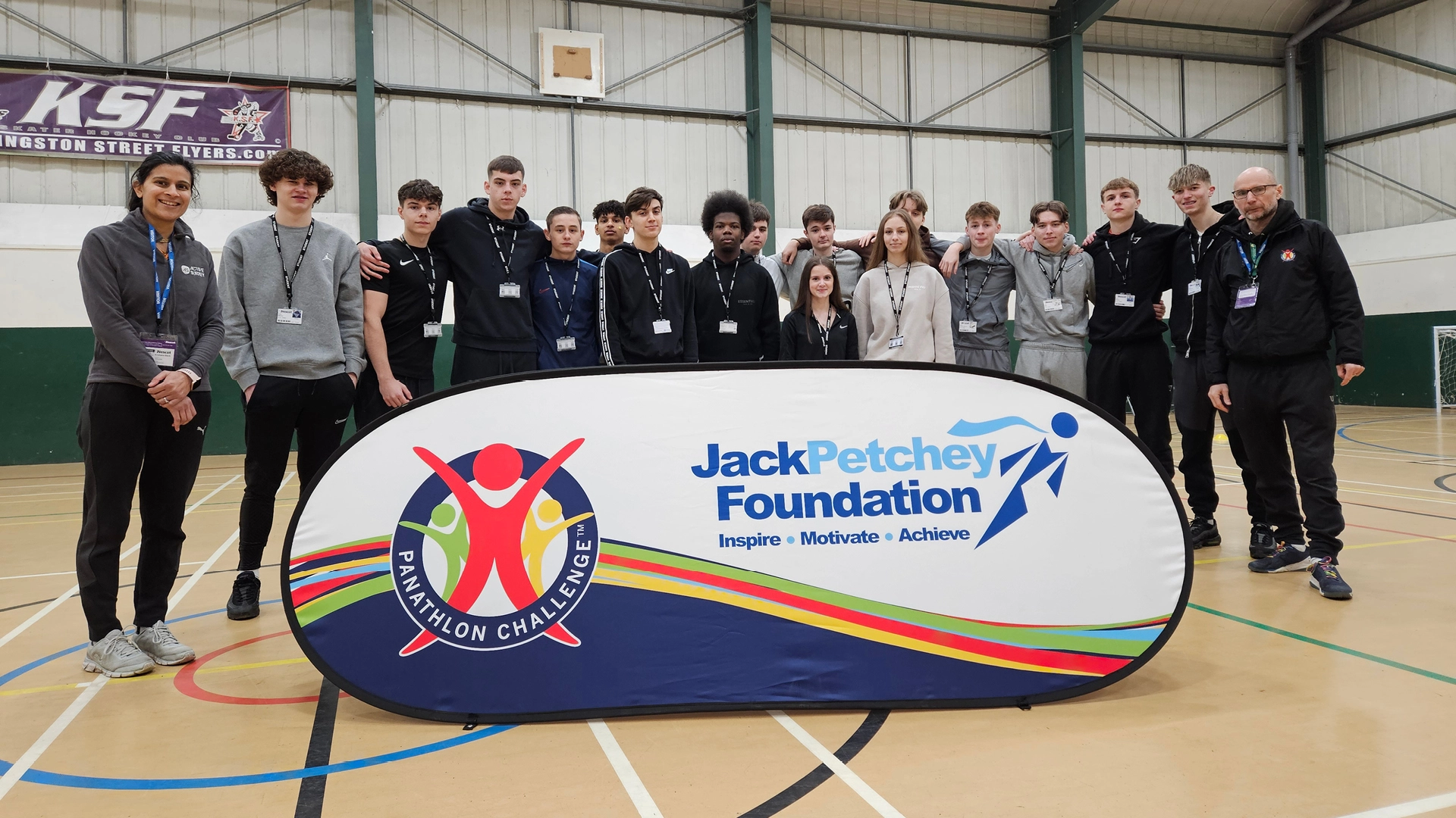 Group of students standing in a sports hall behind a large “Jack Petchey Foundation Panathlon Challenge” banner, with indoor court markings and a Kingston Street Flyers sign visible on the wall.