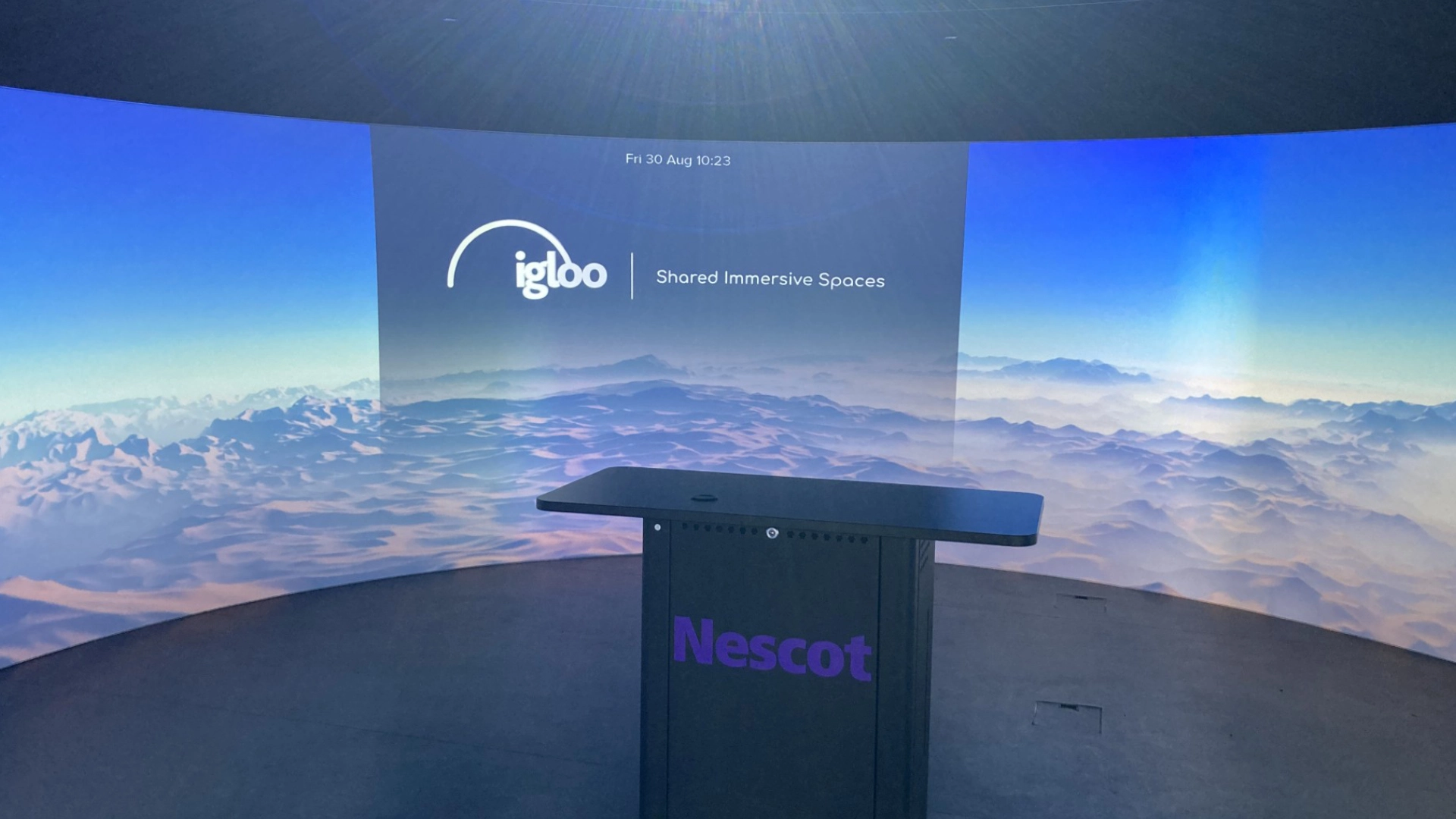 Immersive digital teaching space with curved screen and central podium.