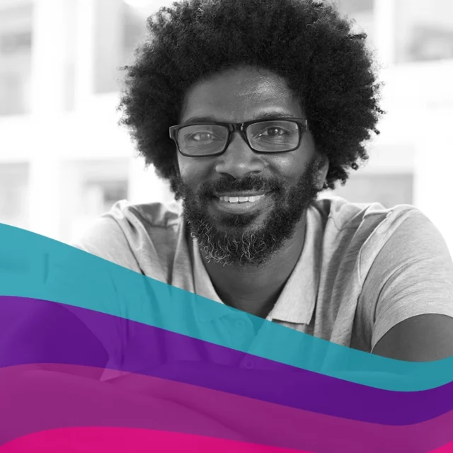 Black‑and‑white portrait of a person with curly hair and glasses, facing the camera, with abstract coloured wave shapes across the lower part of the image.