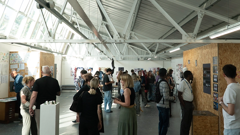 Visitors viewing artwork displayed around an art exhibition space with high ceilings and natural light.