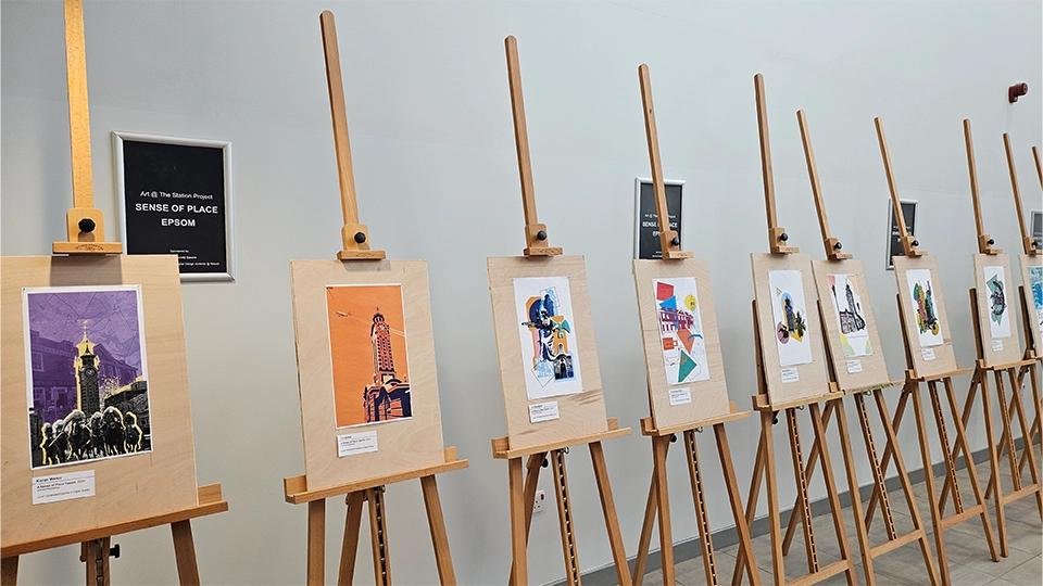 Illustrated posters and prints displayed on easels in a gallery labelled ‘Sense of Place Epsom’.