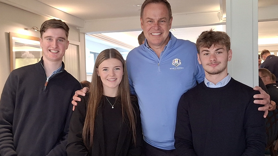 Four people standing together indoors at an event or function.