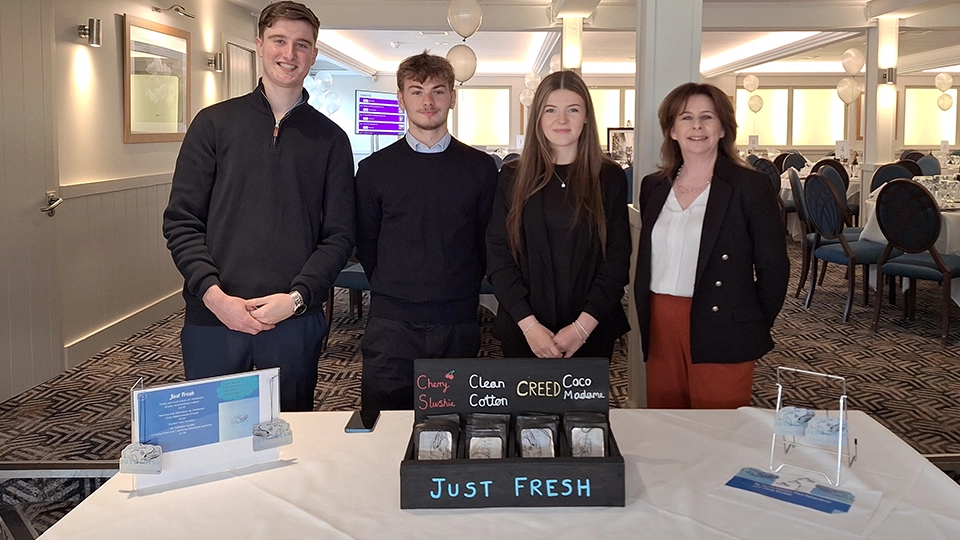 Small group standing behind a table displaying products at an indoor venue.