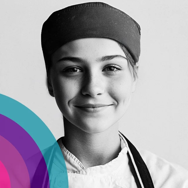 Black and white portrait of a young chef wearing a hat and uniform, facing the camera.