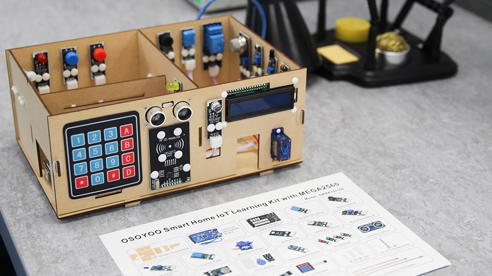 Smart home electronics kit with keypad, display, sensors and wiring modules on a desk