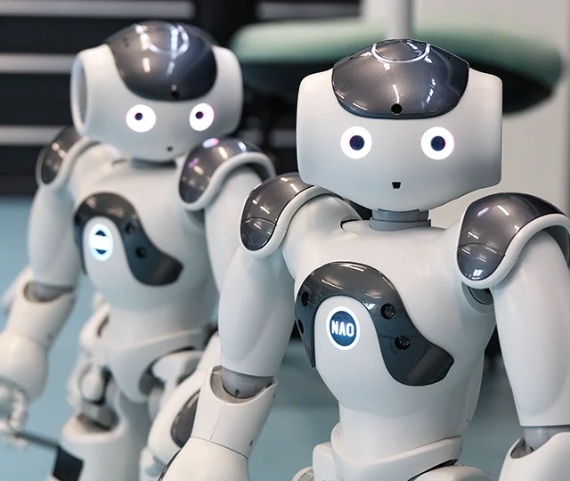 Two humanoid robots standing side by side on a lab floor