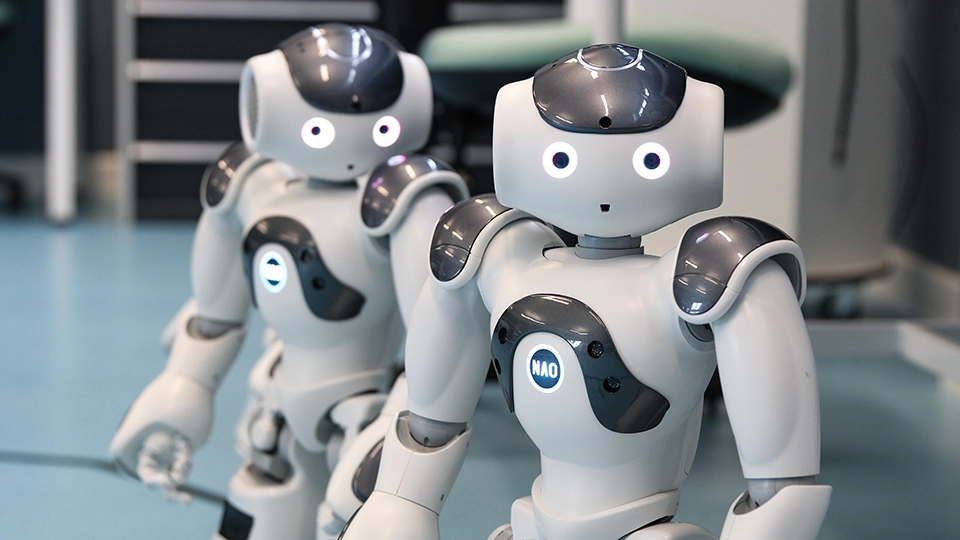 Two humanoid robots standing side by side on a lab floor