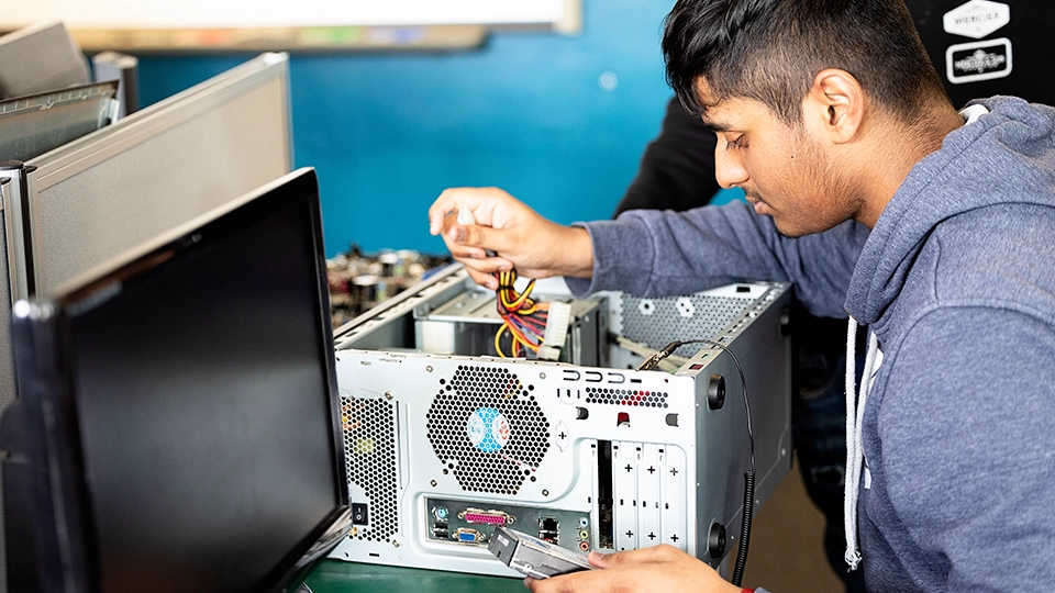 Student connecting cables inside an open desktop computer case