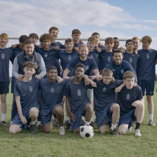 Football team posing for a group photo on a football pitch.
