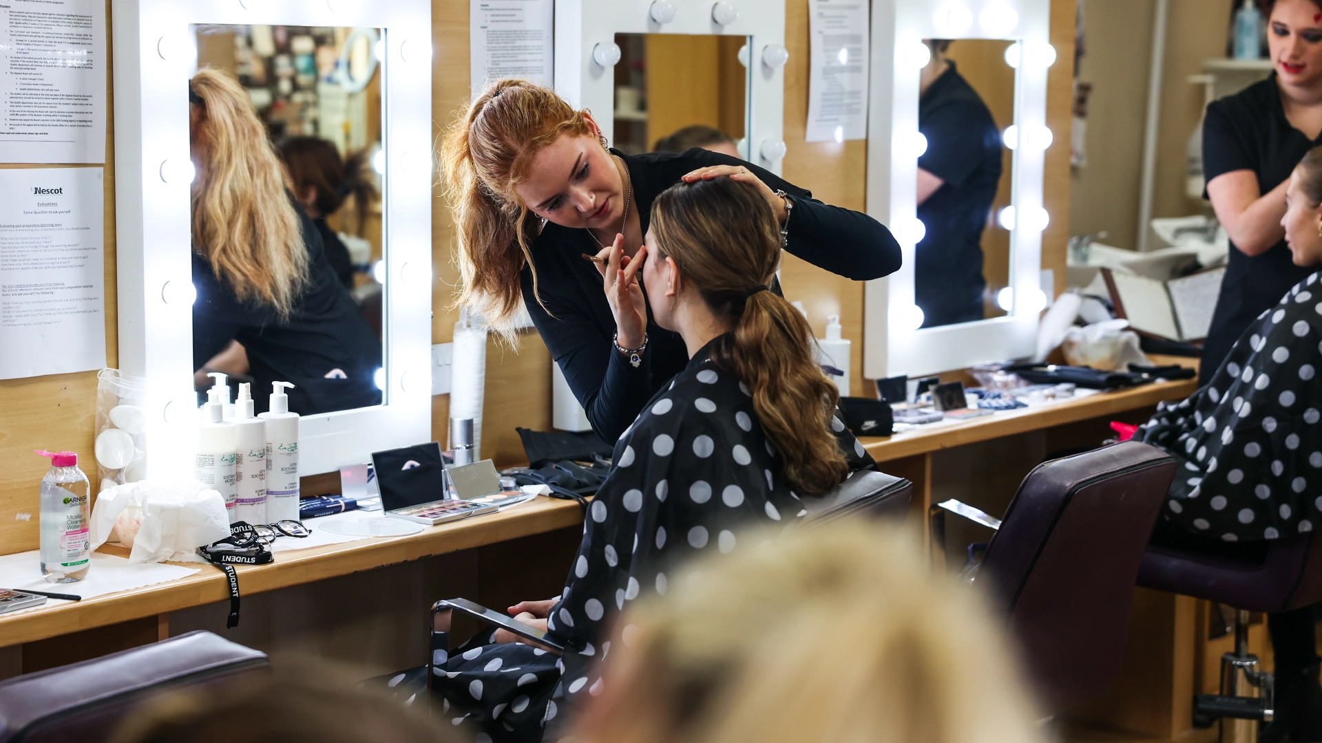 Student applying make-up to a student model using a brush.