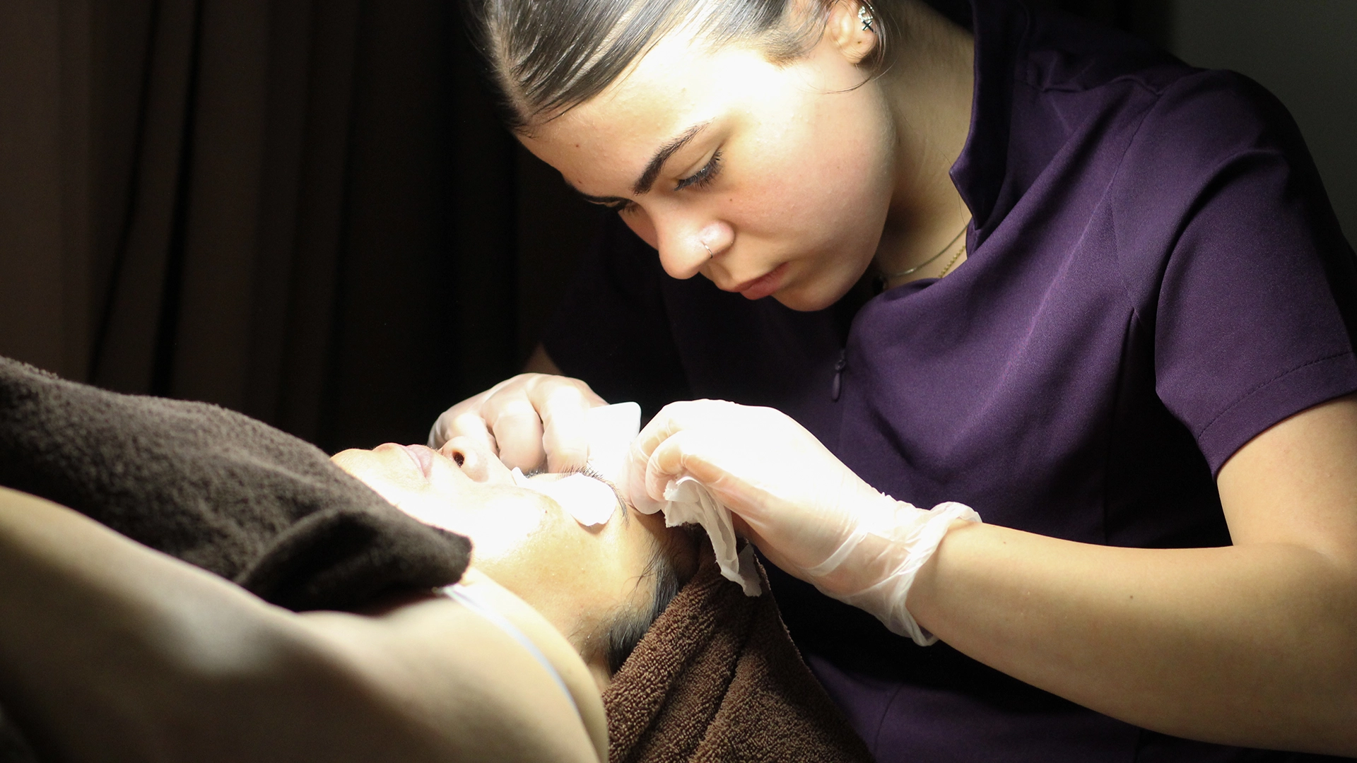 Learner performing a facial treatment on a client.