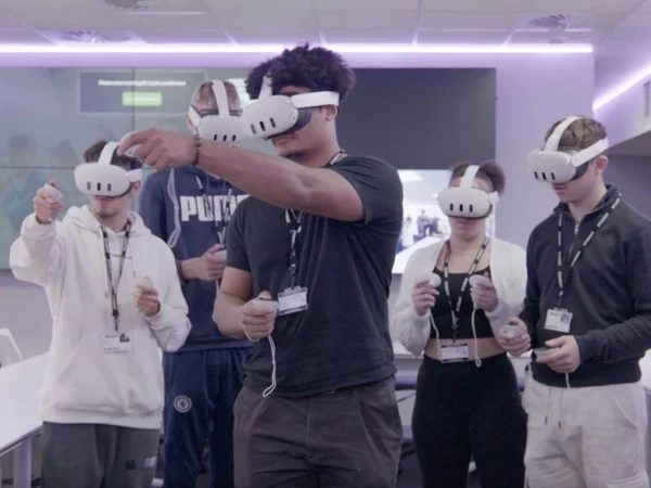 Nescot students wearing VR headsets use handheld controllers in a classroom, taking part in an immersive learning activity together.