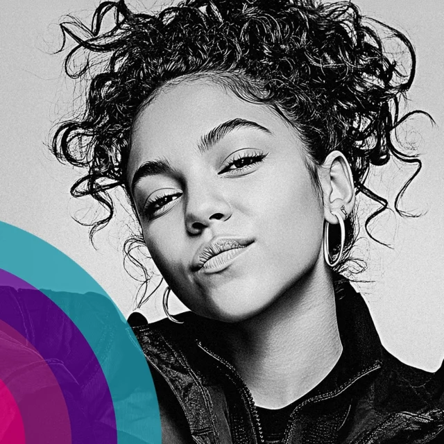 Portrait of a person with short, curly hair and hoop earrings, facing the camera against a plain background.