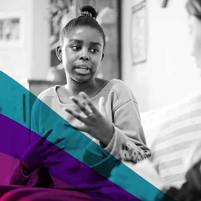 Black-and-white photo of a student sitting on a sofa, speaking and gesturing with their hands while another person listens, suggesting a one-to-one support conversation; teal and pink graphic overlay in foreground.