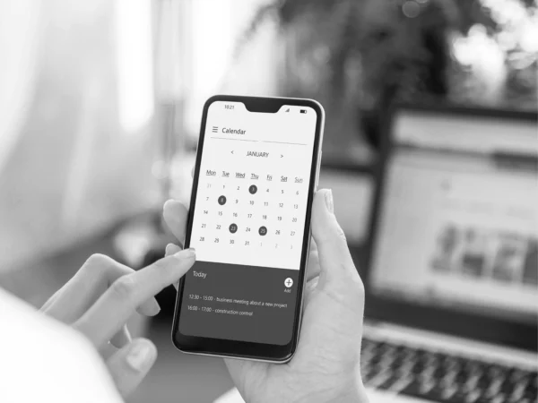 person holding mobile phone with calendar app on screen