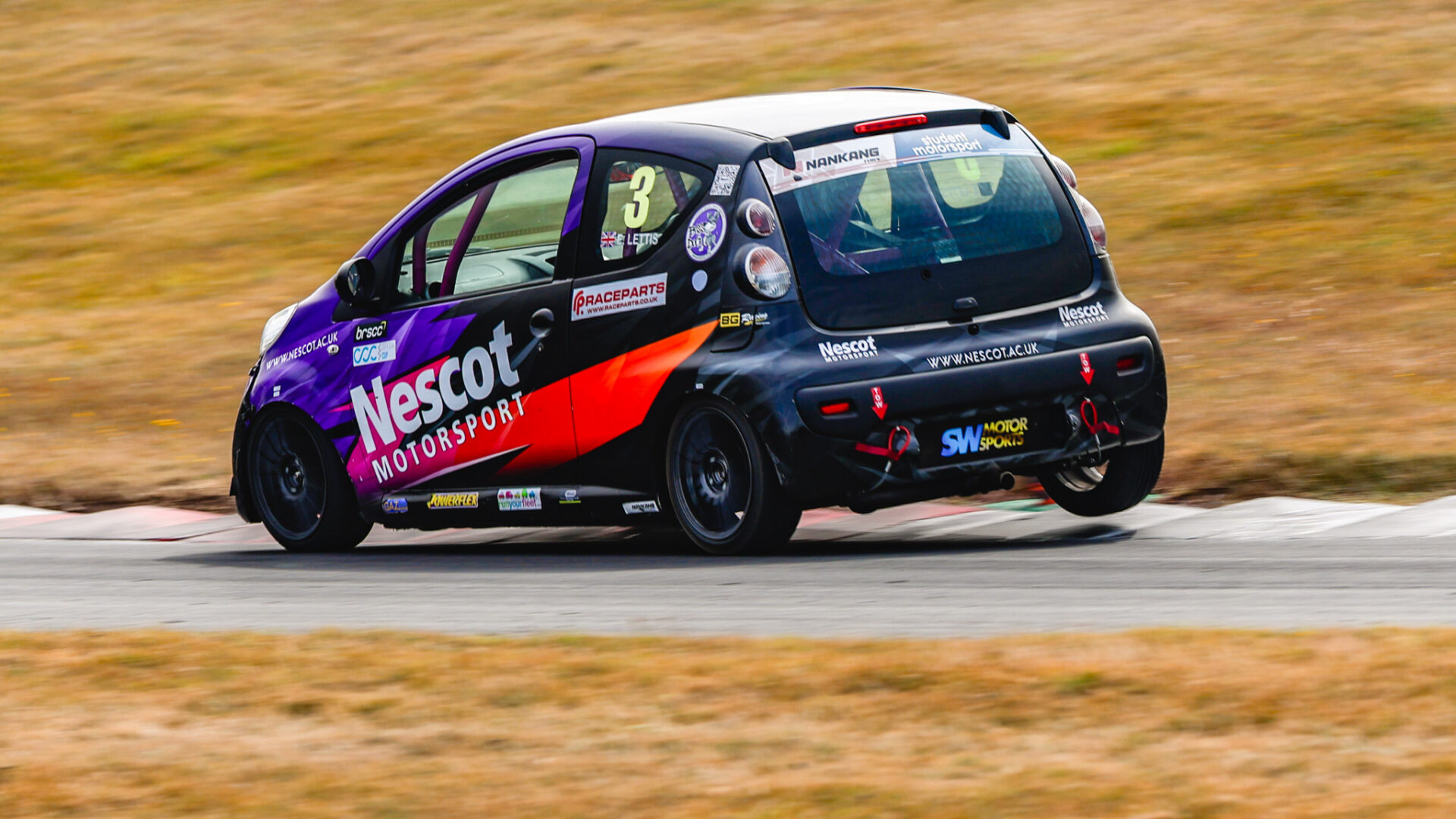 The Nescot Motorsport race car, driven by Elliot Lettis, rounds a corner at speed during a Student Motorsport race weekend at Cadwell Park.
