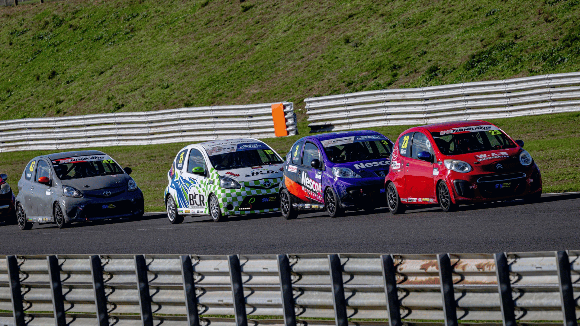 The Nescot Motorsport race car competes in a tightly packed group at Snetterton Circuit, battling for position during a Student Motorsport race