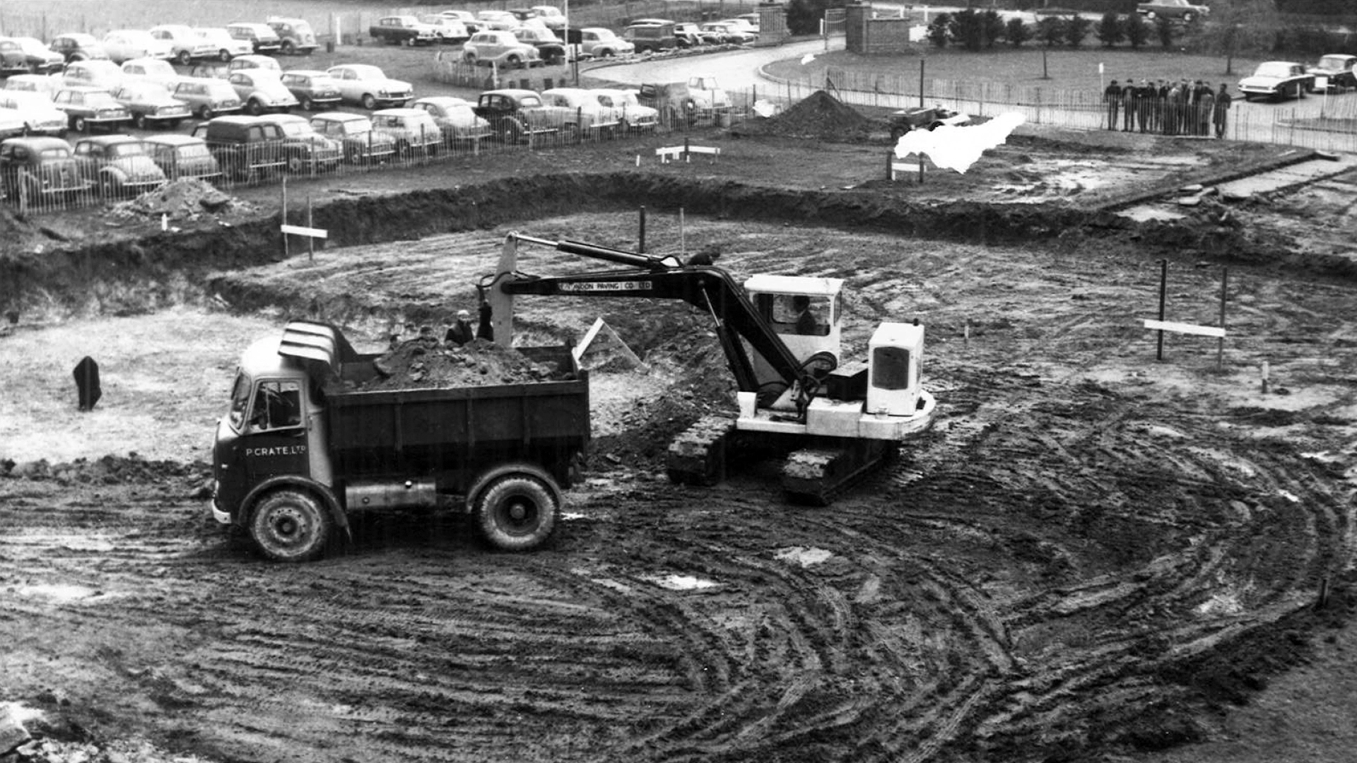 Historic black and white photo of the construction site showing an earth mover and trailer clearing the site.