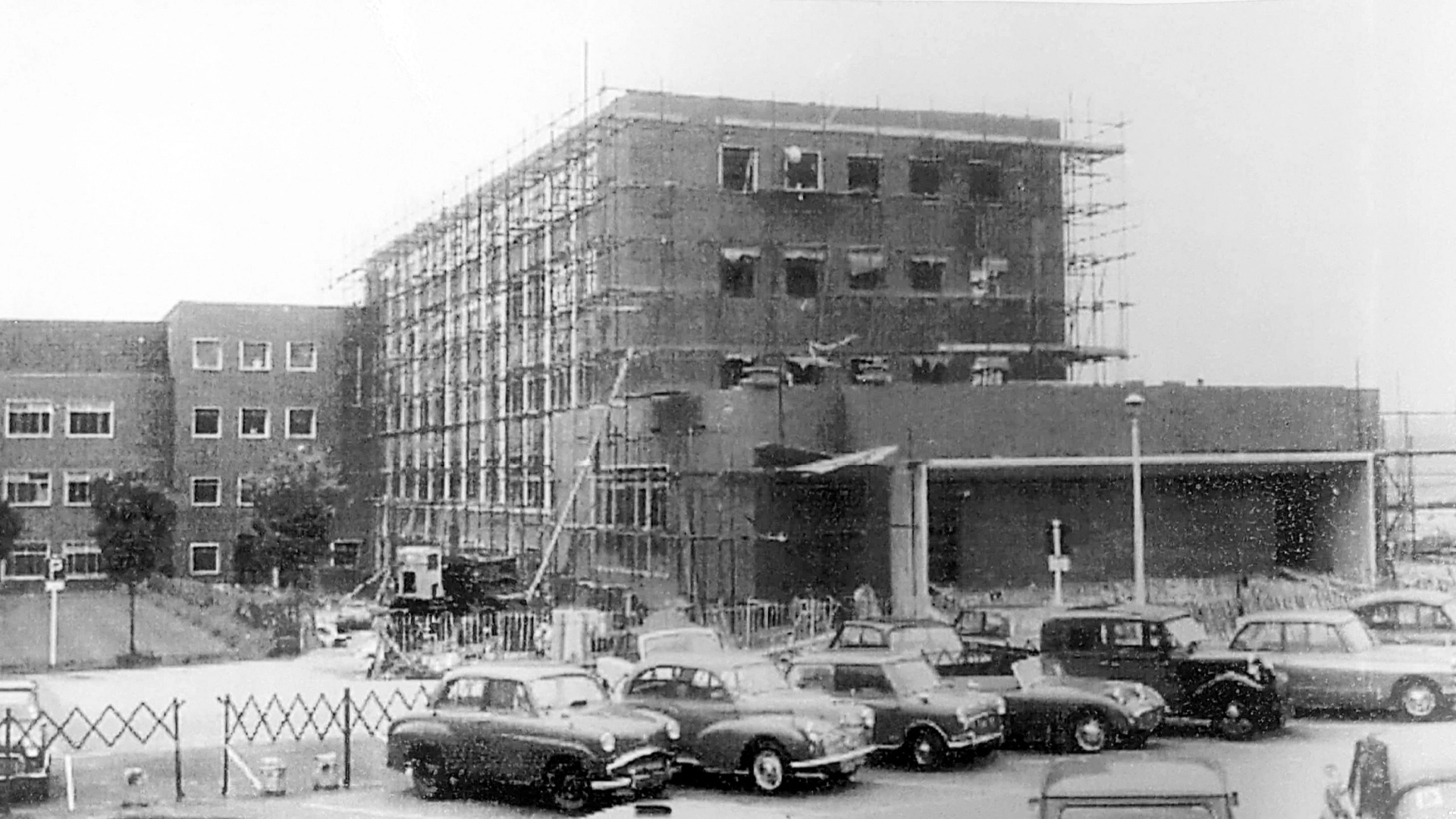 Historic black and white photo showing the progress of construction of a new four-storey extension in 1964
