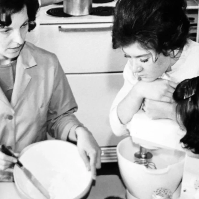 Historic black and white photo of Home Economics students and teacher using a food mixer